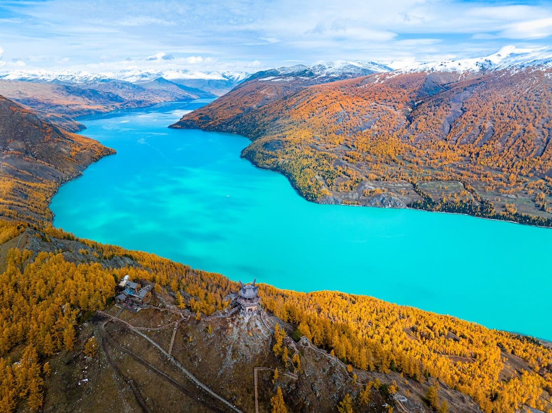 Kanas Lake surrounded by mountains and autumn forest